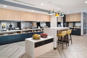 Una cocina moderna con una isla central, taburetes de bar y un fabricante de gofres.