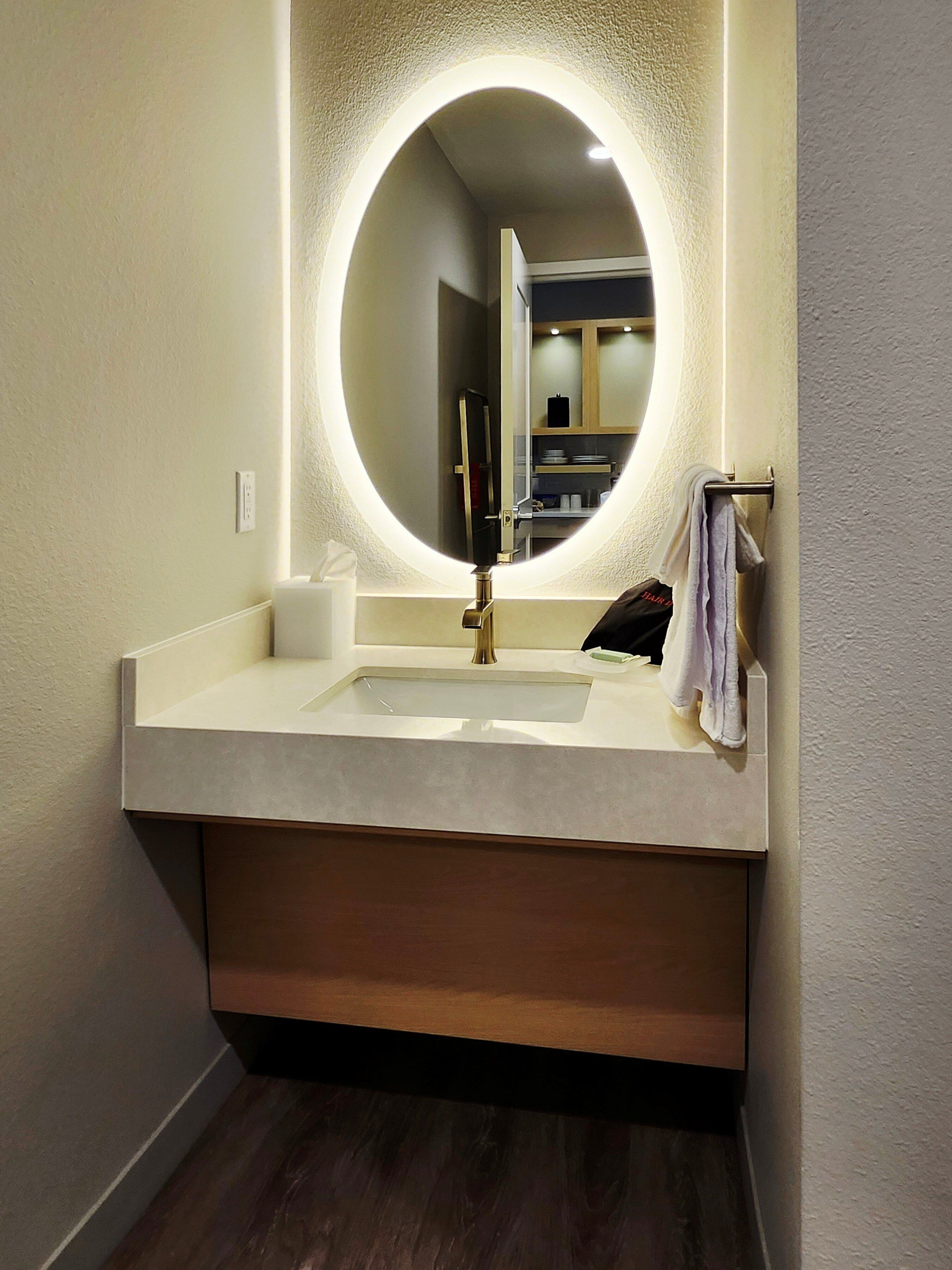 A bathroom with a round mirror, a sink, and a towel rack.