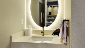 A bathroom with a round mirror, a sink, and a towel rack.