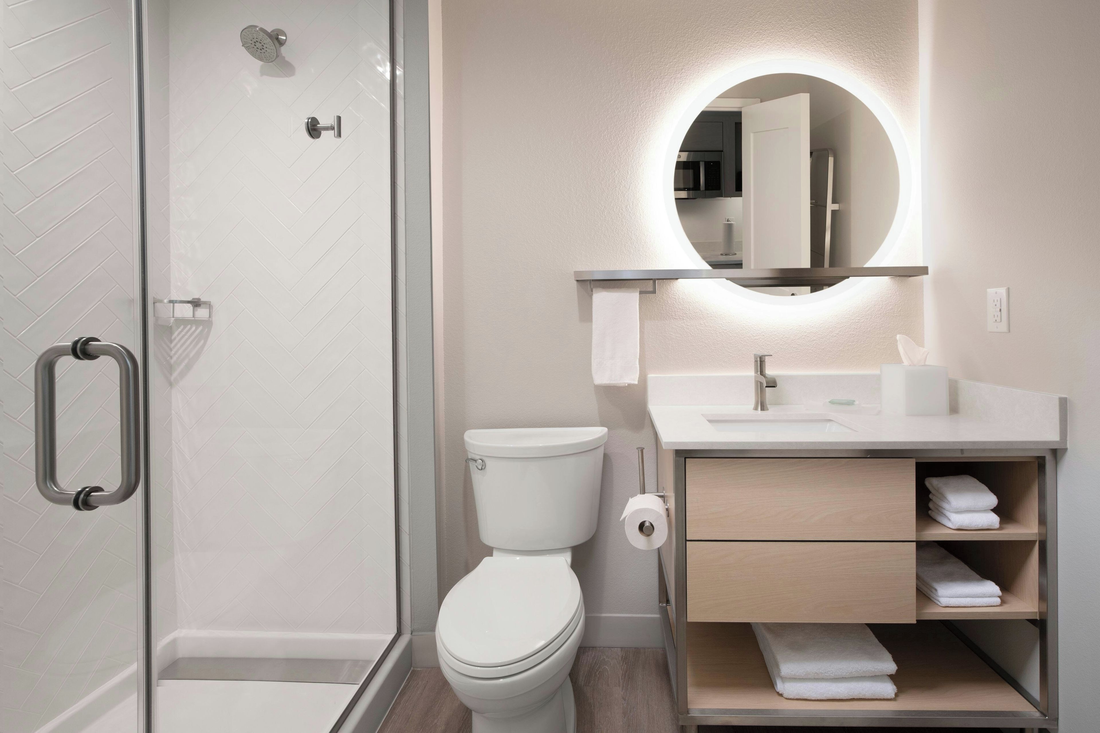 A modern bathroom with a glass shower enclosure, a toilet, a sink with a mirror, and a towel rack.
