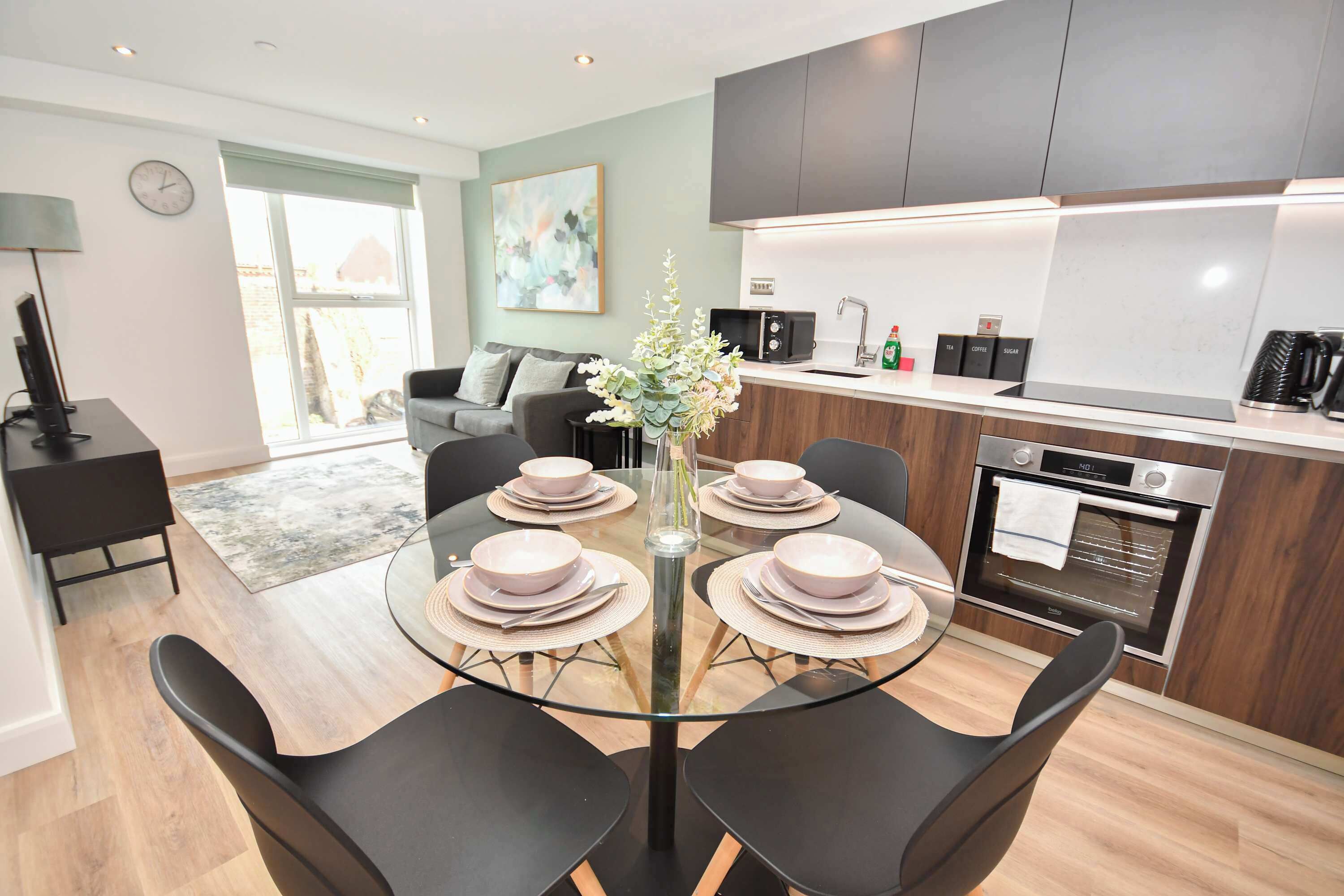 A modern kitchen with a dining area, a coffee machine, and a clock on the wall.