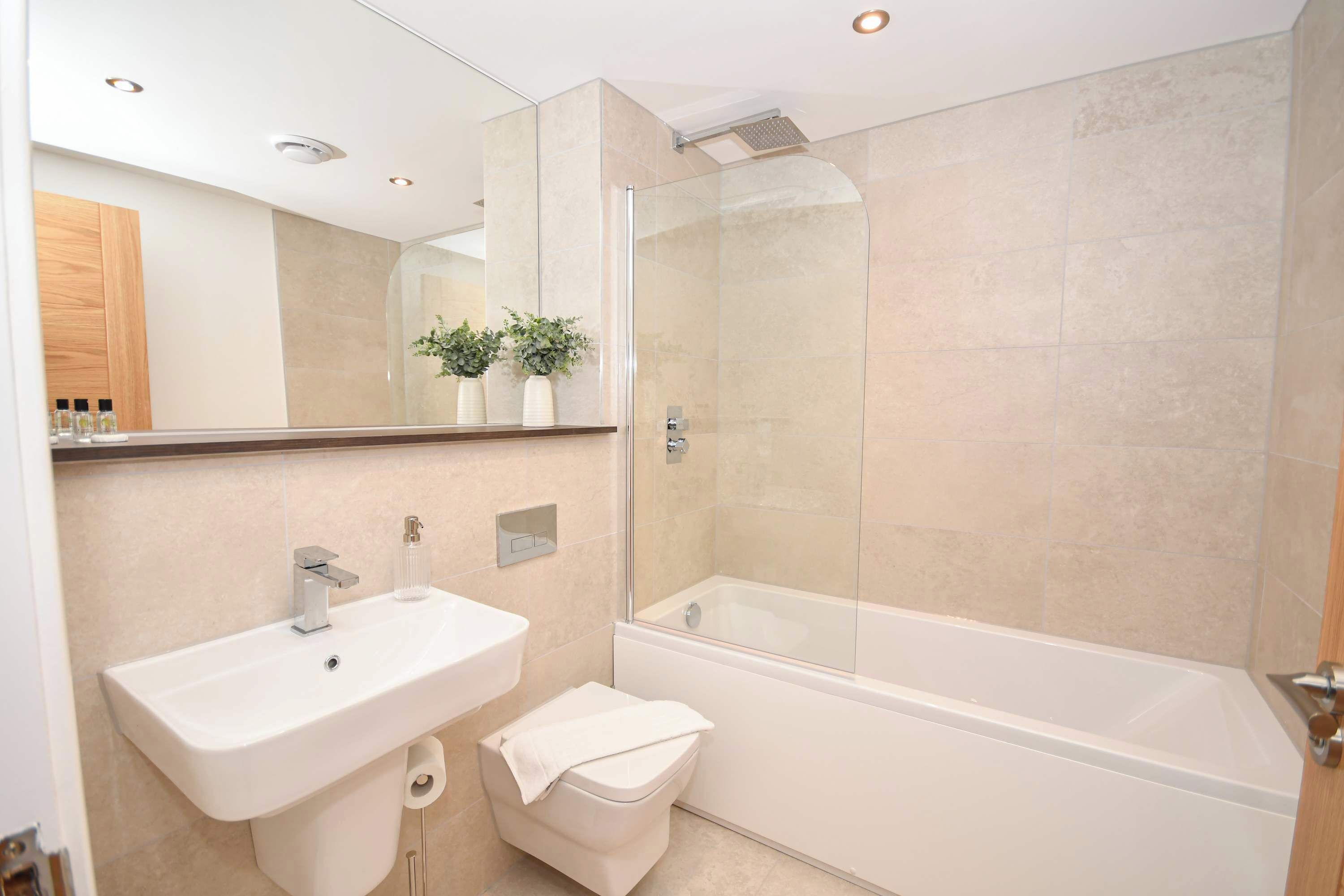 A modern bathroom with a glass-enclosed shower, a white sink, and a toilet.