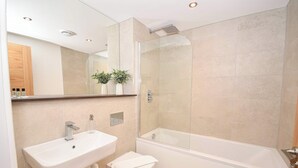 Uma casa de banho moderna com chuveiro de vidro, uma sanita branca e uma pia.