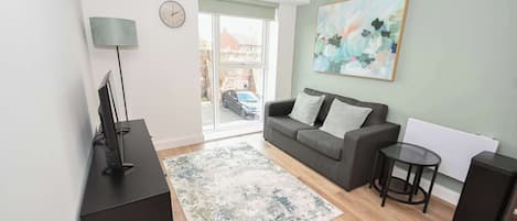 A modern living room with a sofa, a coffee table, a TV, and a painting on the wall.