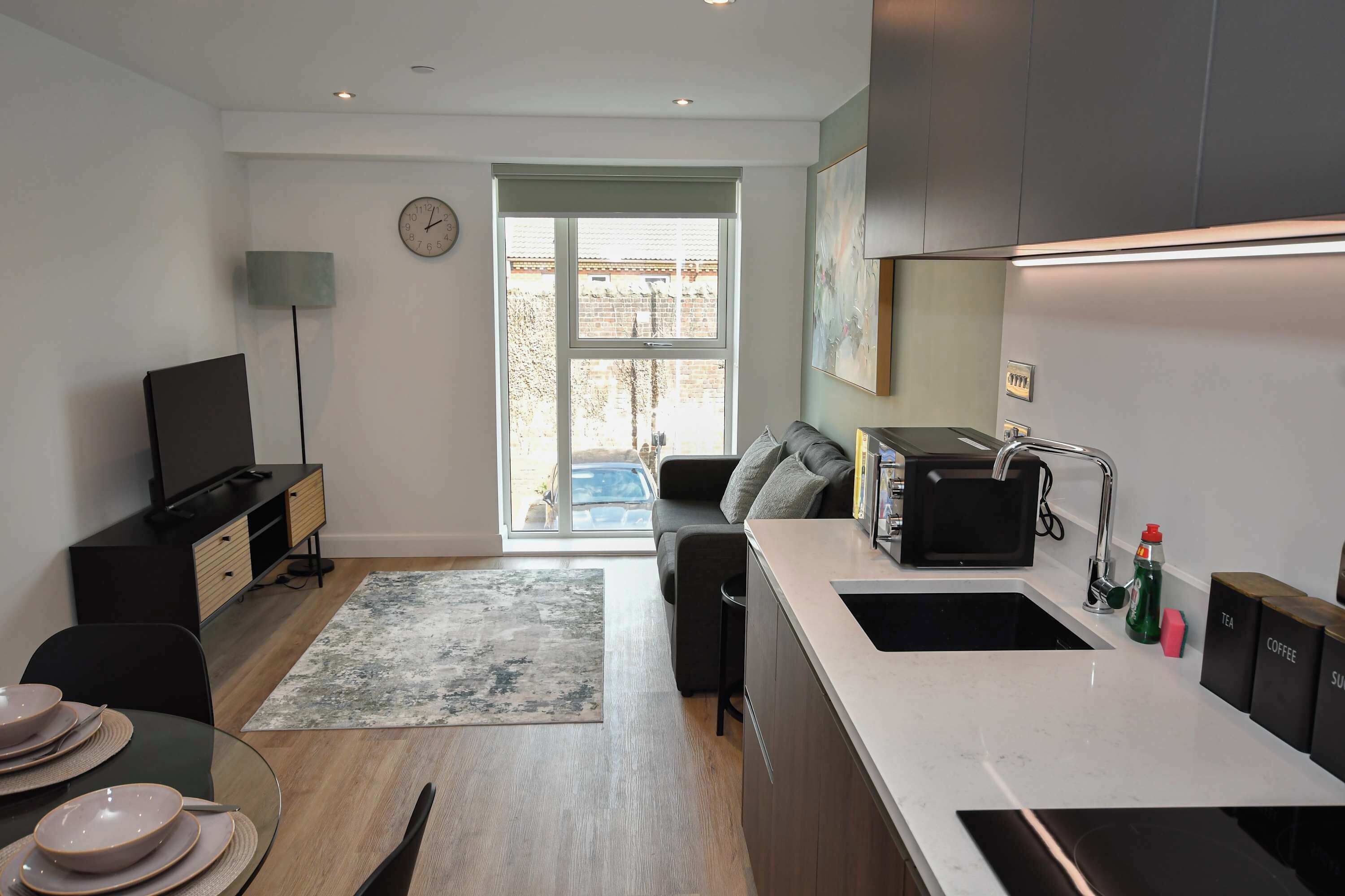 A modern kitchen with a built-in sink, a dining area with a round table, and a living space with a sofa.