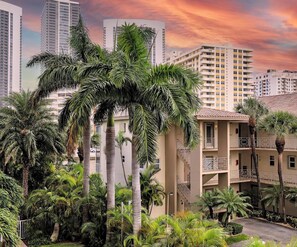 A residential building with multiple balconies, surrounded by lush palm trees. - Beachwalk 2BR Resort Style - Intracoastal View (Hallandale Beach)