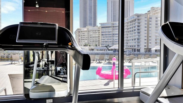 Ein Fitnessraum mit Trainingsgeräten und Blick auf einen Pool mit einem Flamingo-Schwimmpunkt.