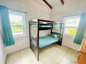 Une chambre avec un lit superposé, une fenêtre d’un côté et une porte de l’autre.