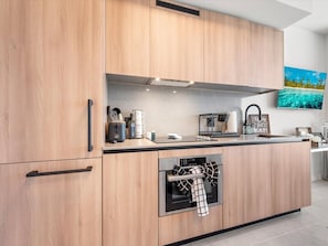 Eine moderne Küche mit Holzschränken, einem eingebauten Backofen und einer Arbeitsplatte mit diversen Küchenutensilien.