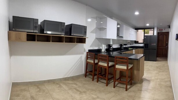 Una cocina moderna con electrodomésticos integrados, una isla central con taburetes altos y un refrigerador al fondo.