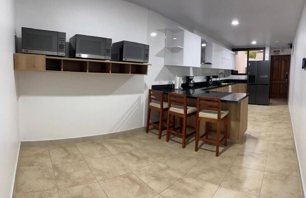 A modern kitchen with built-in appliances, a wooden dining set, and a curved island.