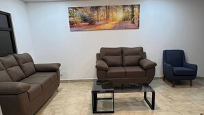 Una sala de estar con un sofá marrón, un sillón azul y una mesa de centro.