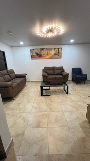 A living room with a brown sofa, a blue armchair, and a coffee table.