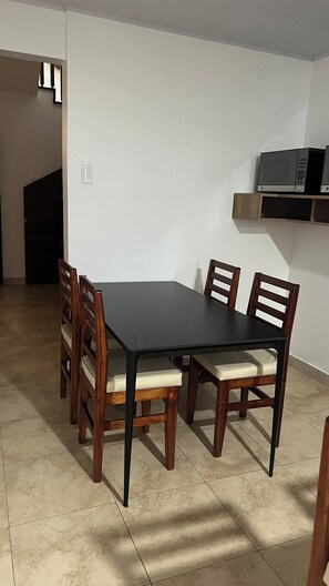 Comedor con mesa rectangular y seis sillas de madera con asientos acolchados.