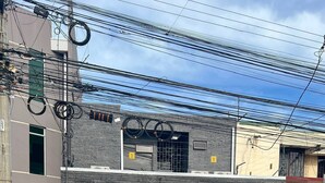 Un edificio residencial con puerta de garaje, acceso mediante portón y varias líneas eléctricas aéreas.