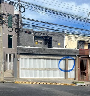 A residential building with a garage door, a gated entrance, and multiple power lines overhead.