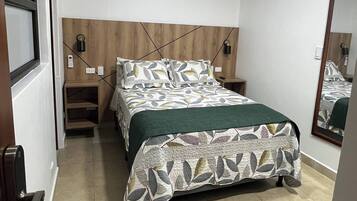 A bedroom with a bed, bedside tables, a mirror, and a door.