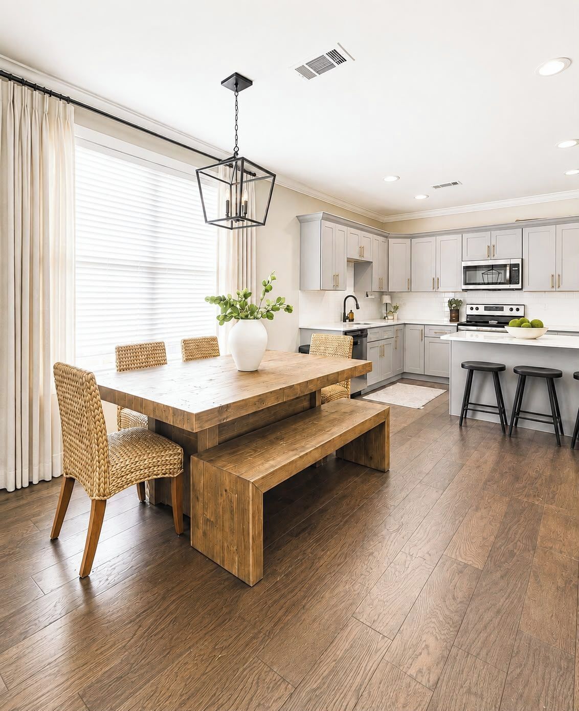 A modern kitchen with white cabinets, a wooden dining table, and a built-in oven.