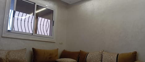 A corner room with a sofa, a table, and a window with metal bars.