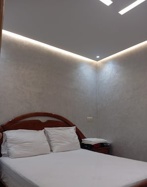Un dormitorio con una cama, cabecera de madera y una lámpara de pared.