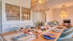 A dining area with a long table set for a meal, a white cabinet with glass doors, and a hanging light fixture. - Finca with pool in Can Treupoc, Porto Cristo (Manacor (Porto Cristo))