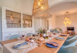 A dining area with a long table set for a meal, a white cabinet with glass doors, and a hanging light fixture. - Finca with pool in Can Treupoc, Porto Cristo (Manacor (Porto Cristo))