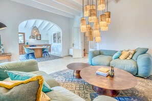 Uma sala de estar ampla, com sofá, mesa de centro e uma área de jantar com cadeiras e mesa.