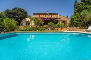 Une piscine avec un bâtiment en pierre en arrière-plan.