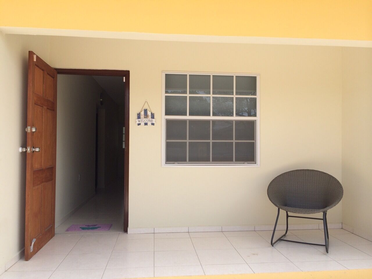 A room with a wooden door, a window, and a chair.