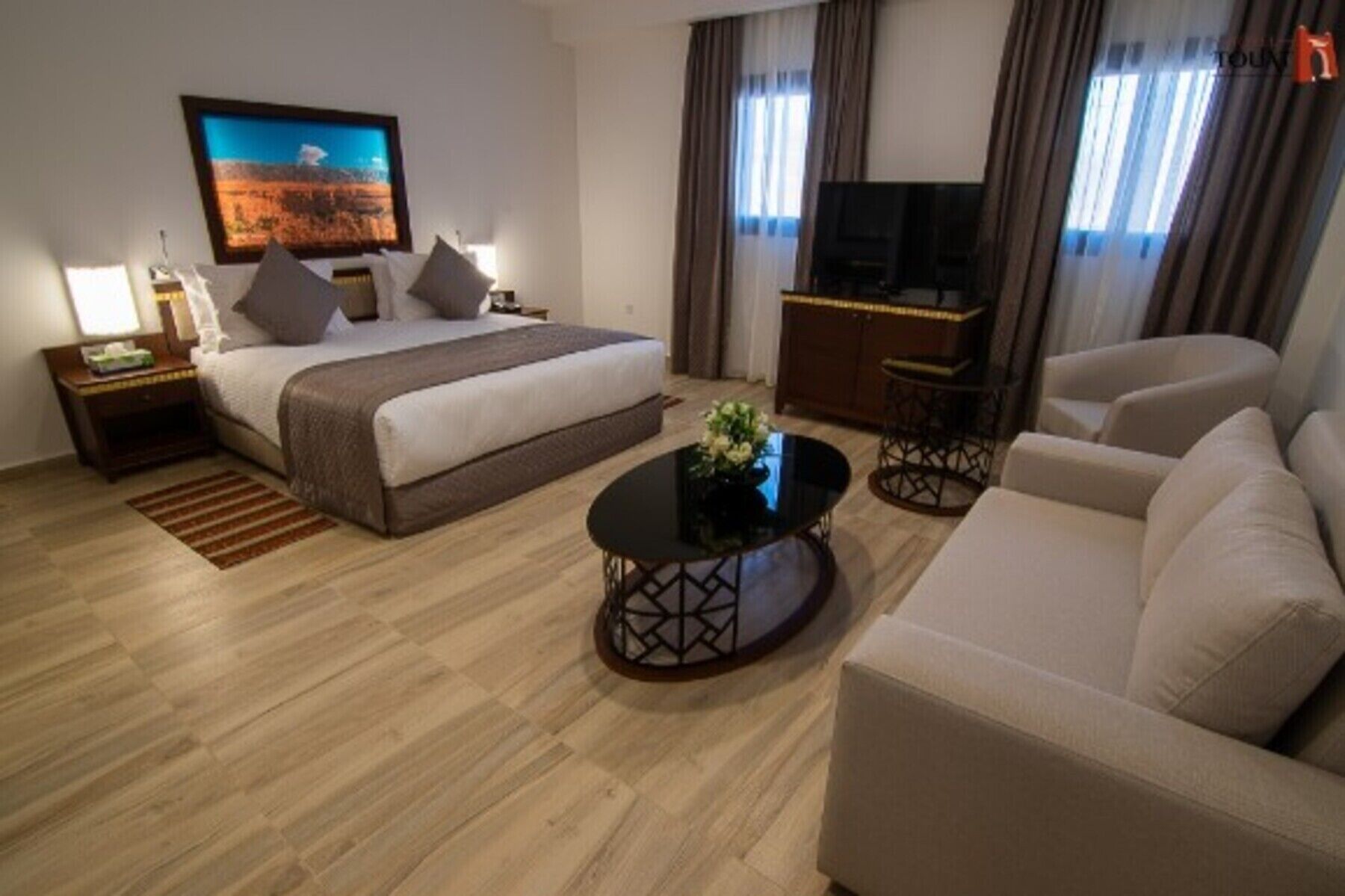 Habitación de hotel con cama, televisión, sofá y mesa de centro.