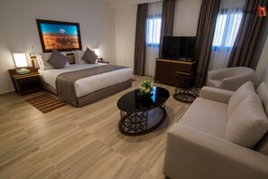 Habitación de hotel con cama, televisión, sofá y mesa de centro.