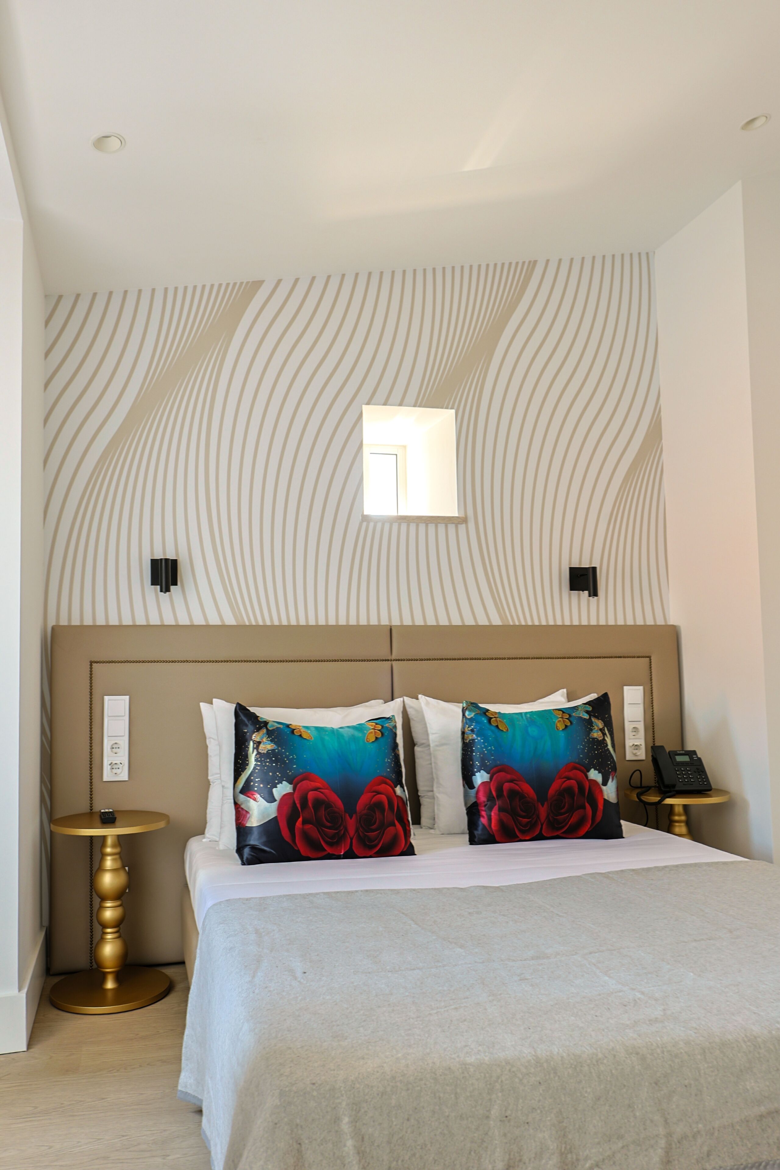 Une chambre d’hôtel comprenant un lit, une table de chevet, une lampe fixée au mur et un téléphone.