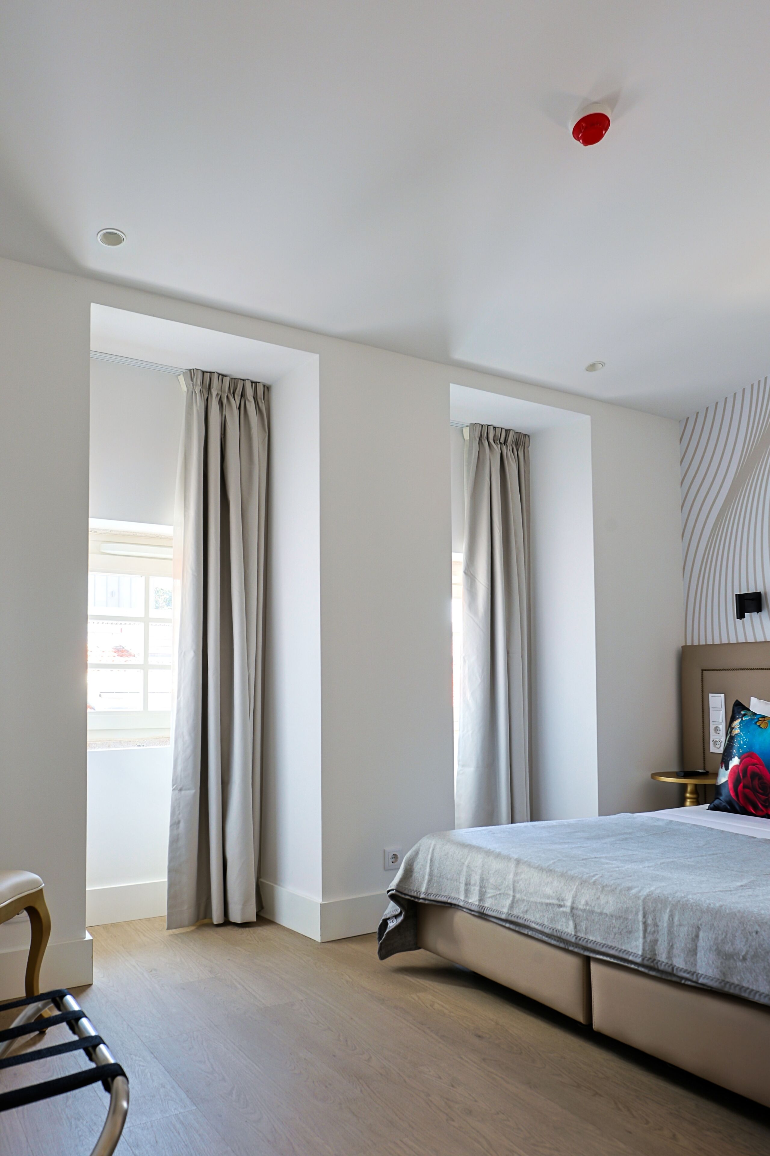 A modern bedroom with a bed, curtains, a chair, and a bedside table.