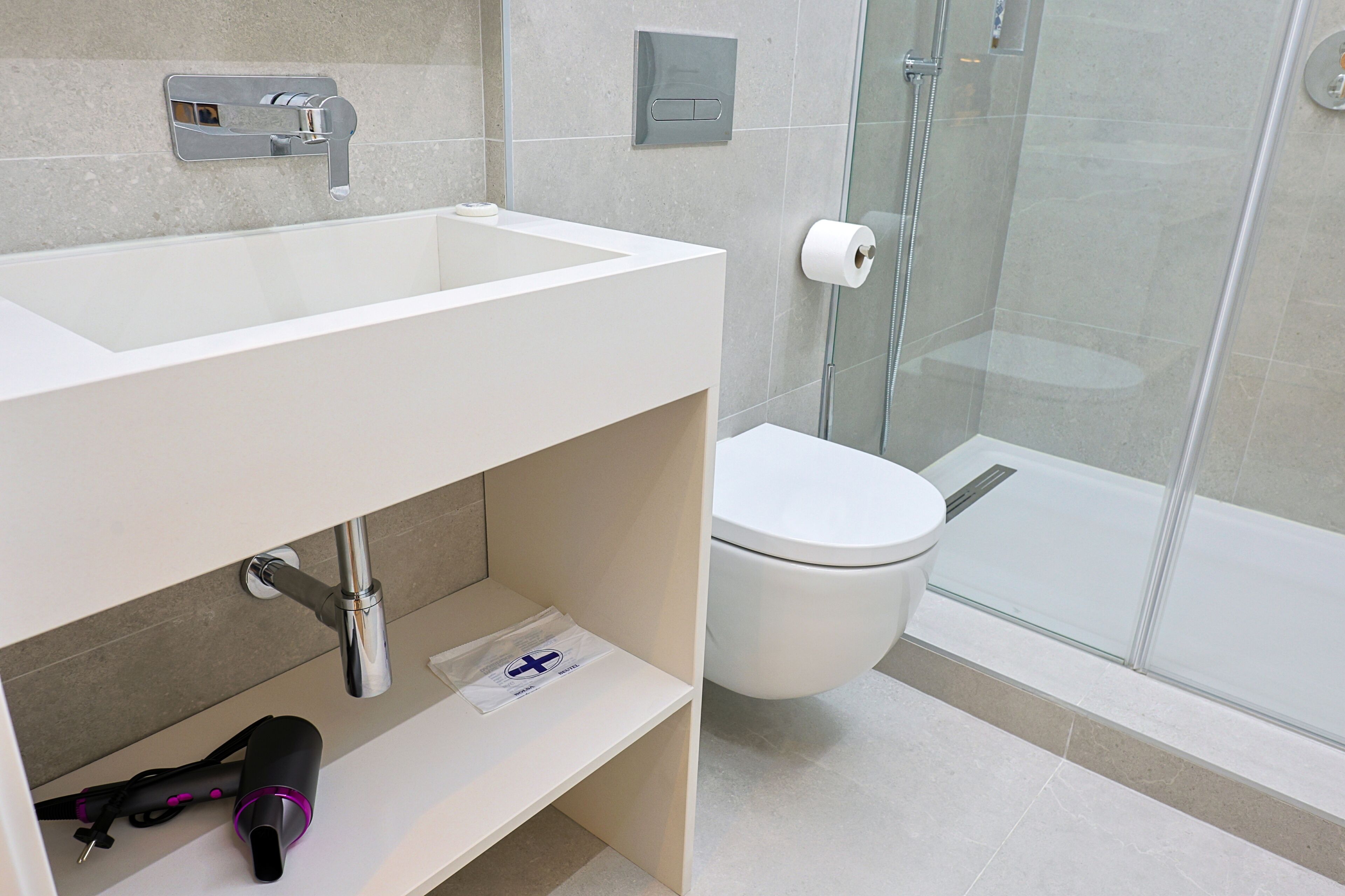 A modern bathroom with a white sink, a toilet, and a glass shower enclosure.
