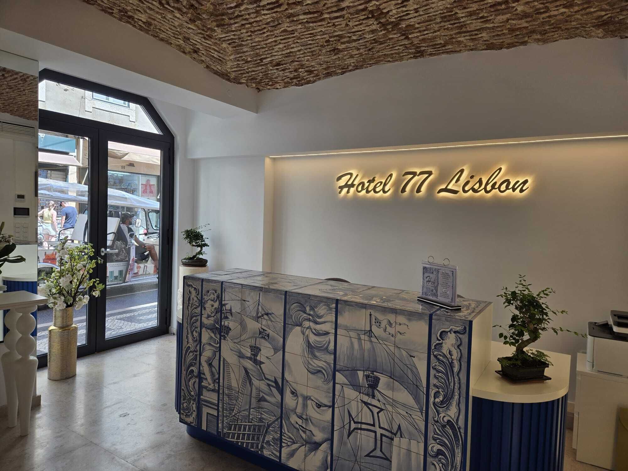 Ein Hotelrezeptionsschalter mit einem großen, beleuchteten Schild, auf dem 'Hotel 77 Lisbon' steht.