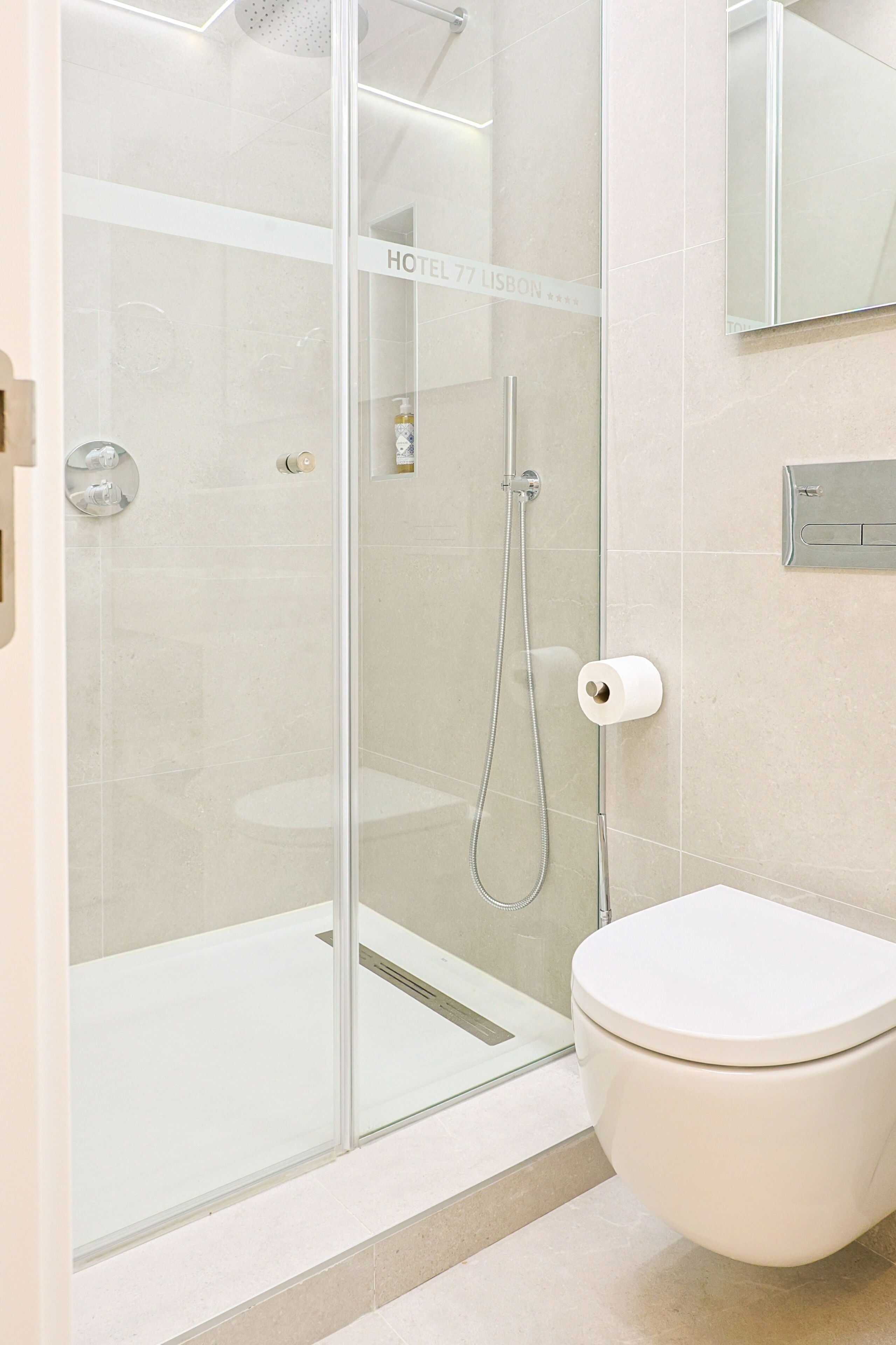 A modern bathroom with a glass-enclosed shower, a toilet, and a towel rack.