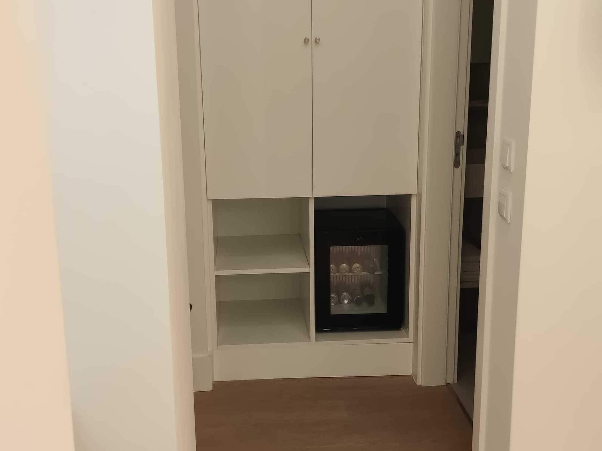 Ein weißer Kleiderschrank mit zwei Türen und ein Regal mit einem schwarzen Gerät.
