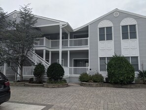 A two-story building with a covered front porch and a staircase leading to the upper level. - Stunning sunset and water views on Bay 2 bedrooms, 3 beds and 2 baths in OCNJ (Ocean City)
