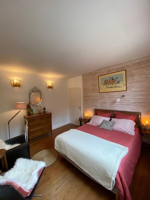 Une chambre à coucher avec un lit, une commode, une chaise et un tableau accroché au mur.