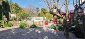 A garden with a statue, a stone wall, and a red structure. - Villa with sea view and private heated pool in the Crozon Peninsula (Finistère) (Landévennec)