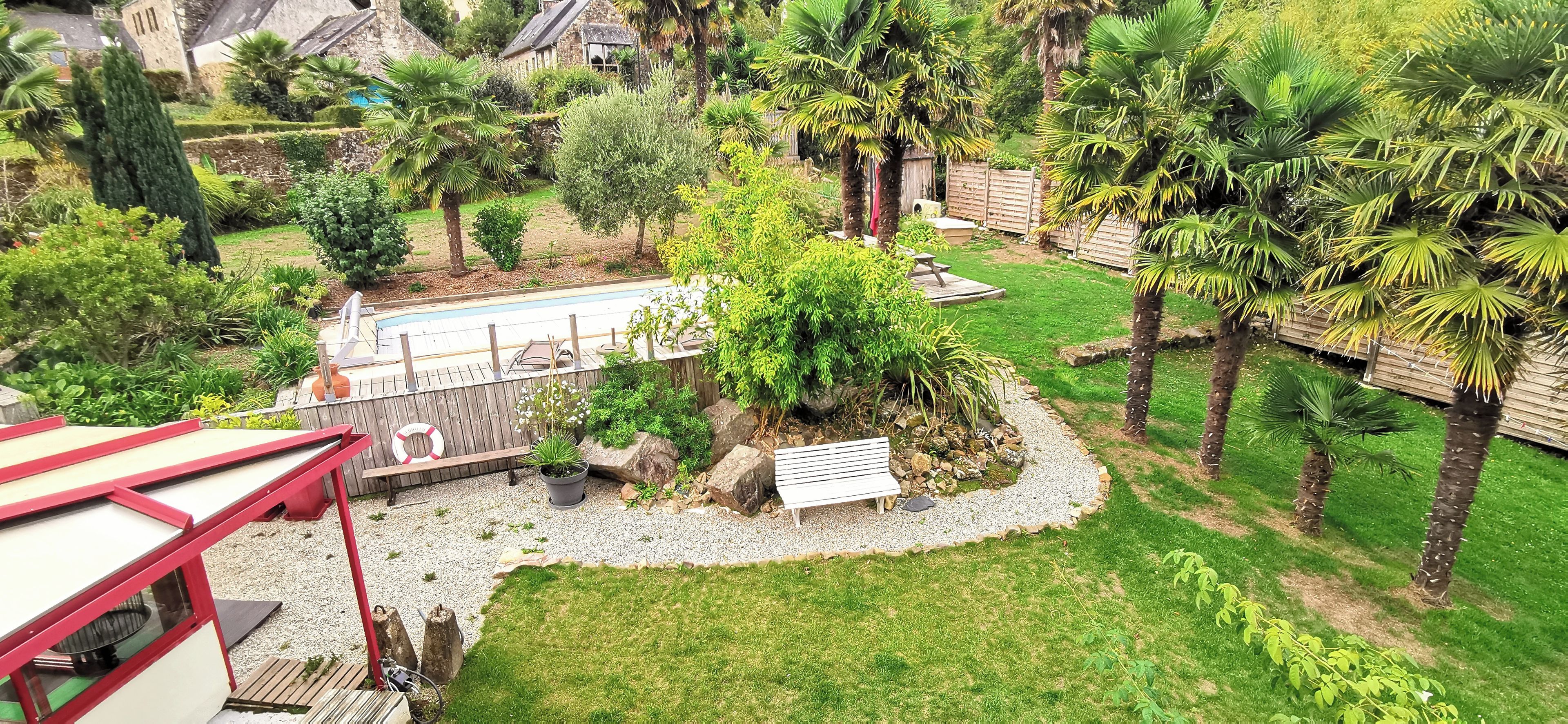 A garden with a pool, a wooden deck, and a bench.