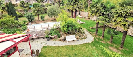A garden with a pool, a wooden deck, and a bench.