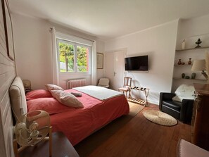 Een slaapkamer met een bed, een stoel, een televisie en een raam.