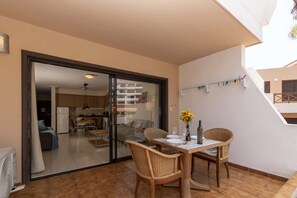 A dining area with a table and chairs, a view into the kitchen, and a balcony with a railing. - Parque Albatross 5 - One Bed Apartment (Golf del Sur)