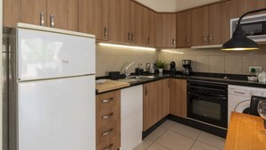 Eine Küche mit Holzausstattung, einem weißen Kühlschrank, einer Spüle, einer Kaffeemaschine und einem Herd.