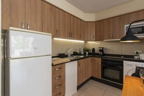 A kitchen with wooden cabinets, a white refrigerator, a sink, a coffee maker, and a stove. - Parque Albatross 5 - One Bed Apartment (Golf del Sur)