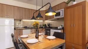 Eine moderne Küche mit Holzschränken, einem Esstisch für vier Personen und einem eingebauten Backofen.