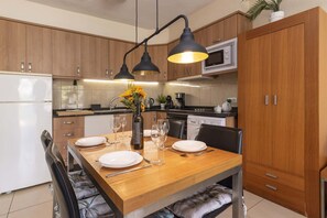 A modern kitchen with wooden cabinets, a dining table set for four, and a built-in oven. - Parque Albatross 5 - One Bed Apartment (Golf del Sur)