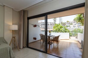 A hotel room with a sliding glass door leading to an outdoor seating area with a table and chairs. - Parque Albatross 5 - One Bed Apartment (Golf del Sur)
