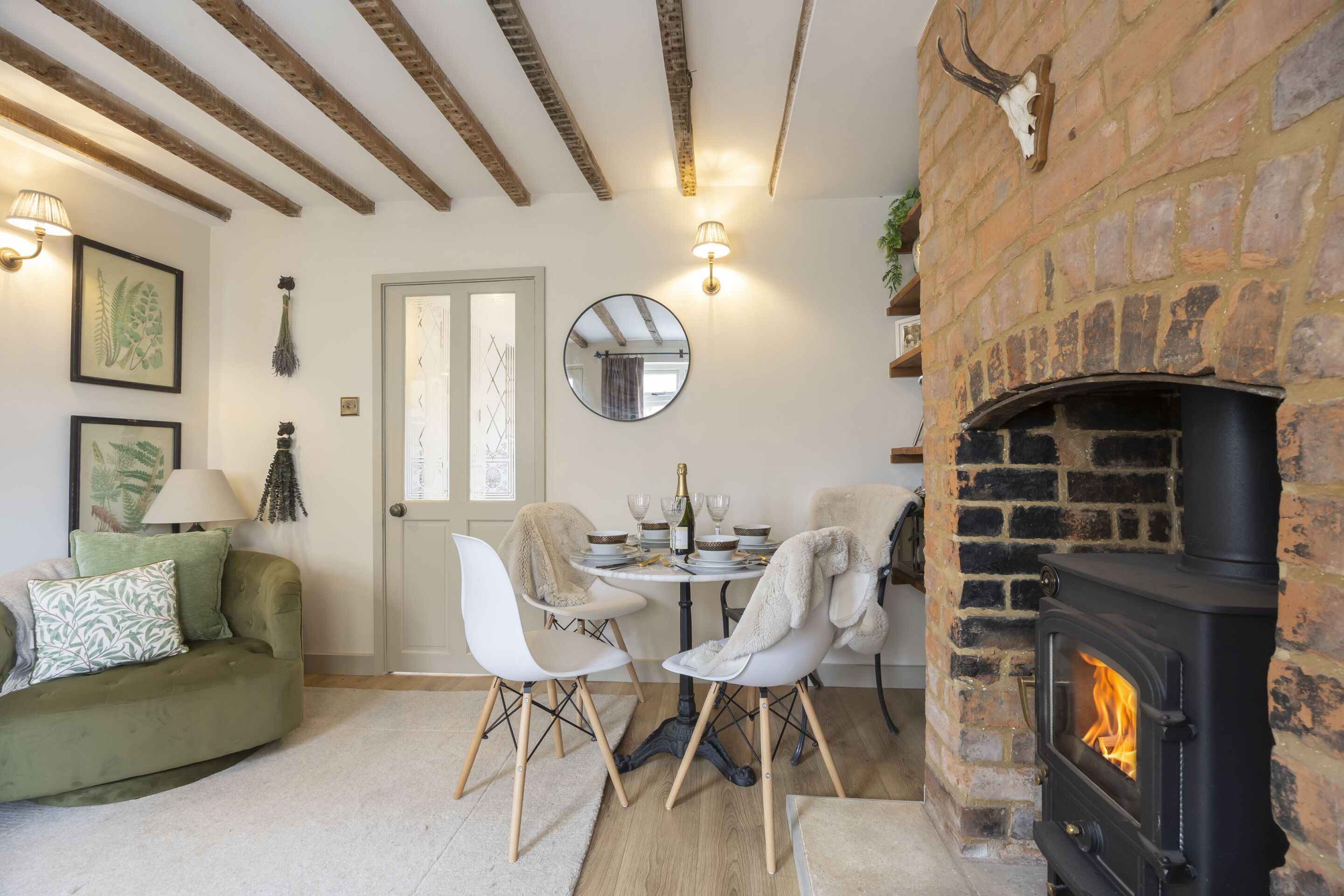 A cozy living room with a fireplace, a dining table set for two, and a green sofa.